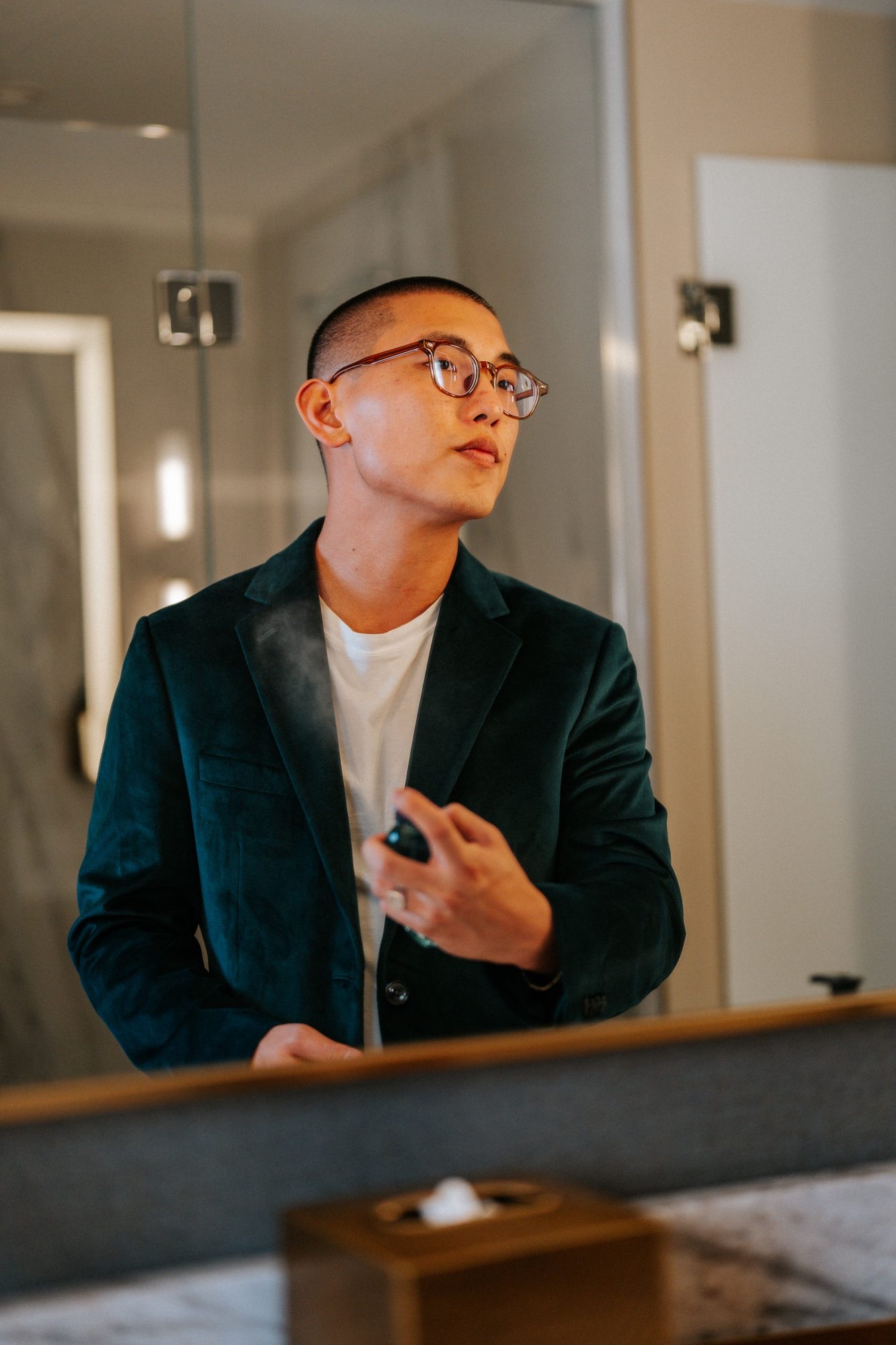 Nicolas Chae in a velvet blazer applying cologne