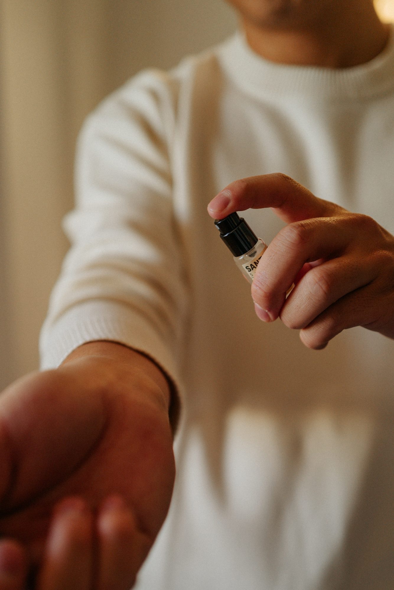Applying cologne from a small glass bottle