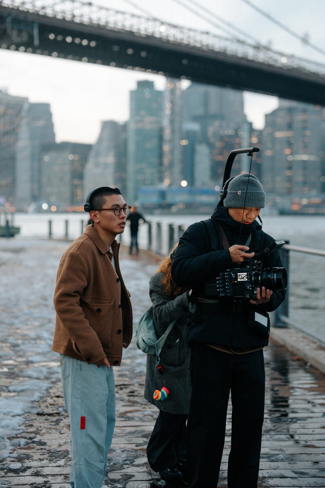 On location with crew under a bridge, NYC skyline in the background