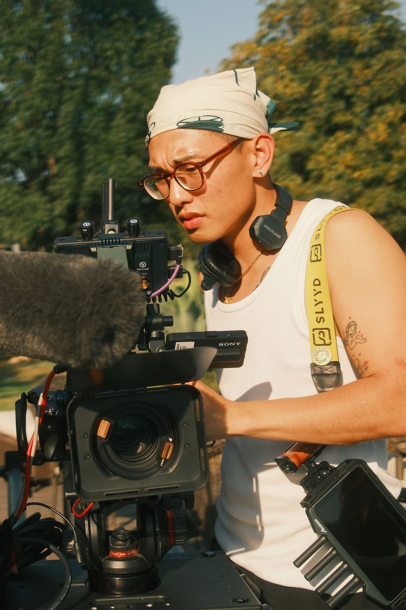 Adjusting a cinema camera rig outdoors with headphones around neck